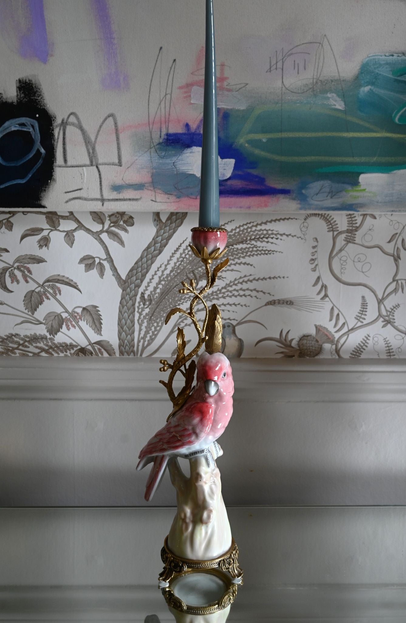 Decorative ceramic candle holder with a pink parrot design against a wall with child's drawings.