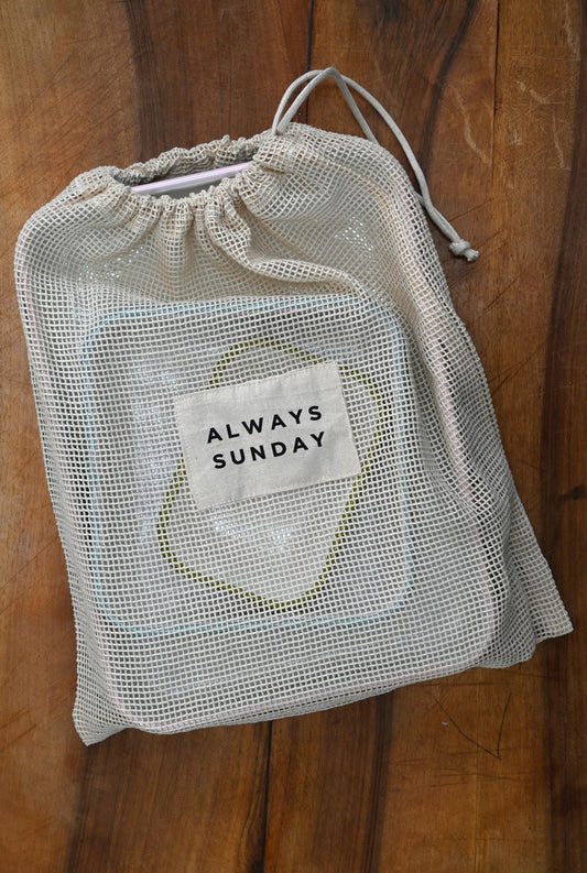 Mesh drawstring bag with 'Always Sunday' label on a wooden surface