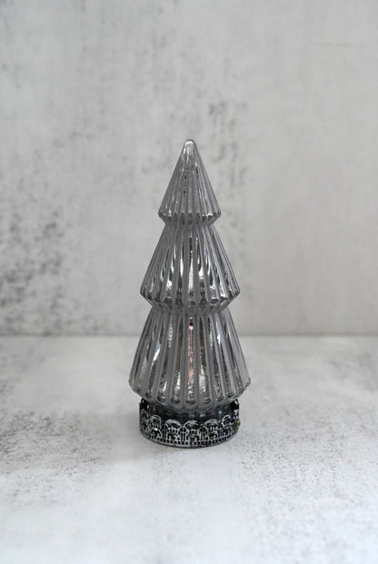 Decorative silver Christmas tree on a white surface with a gray background