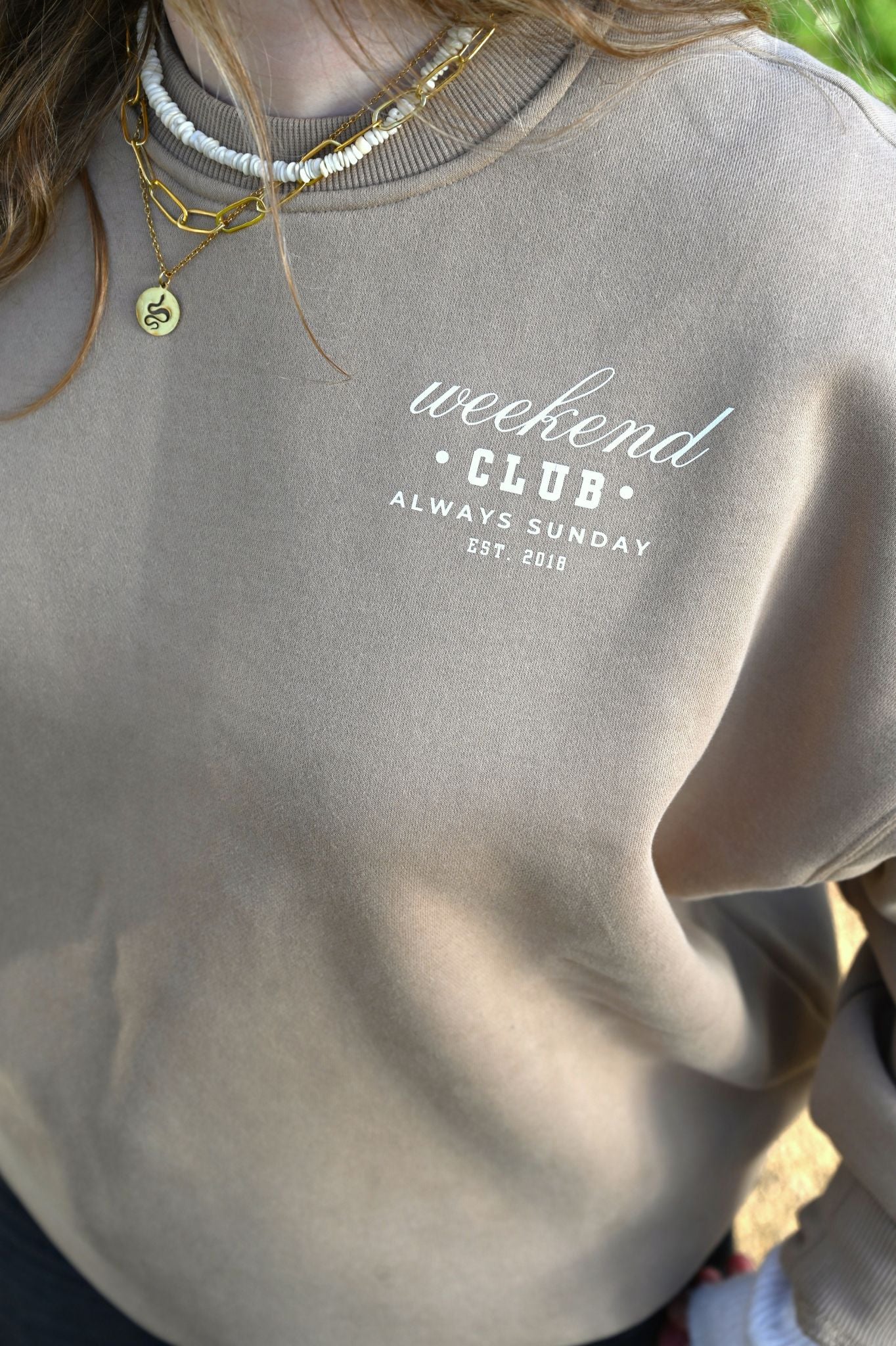 Gray sweatshirt with 'weekend club always sunday' text, worn by a person.
