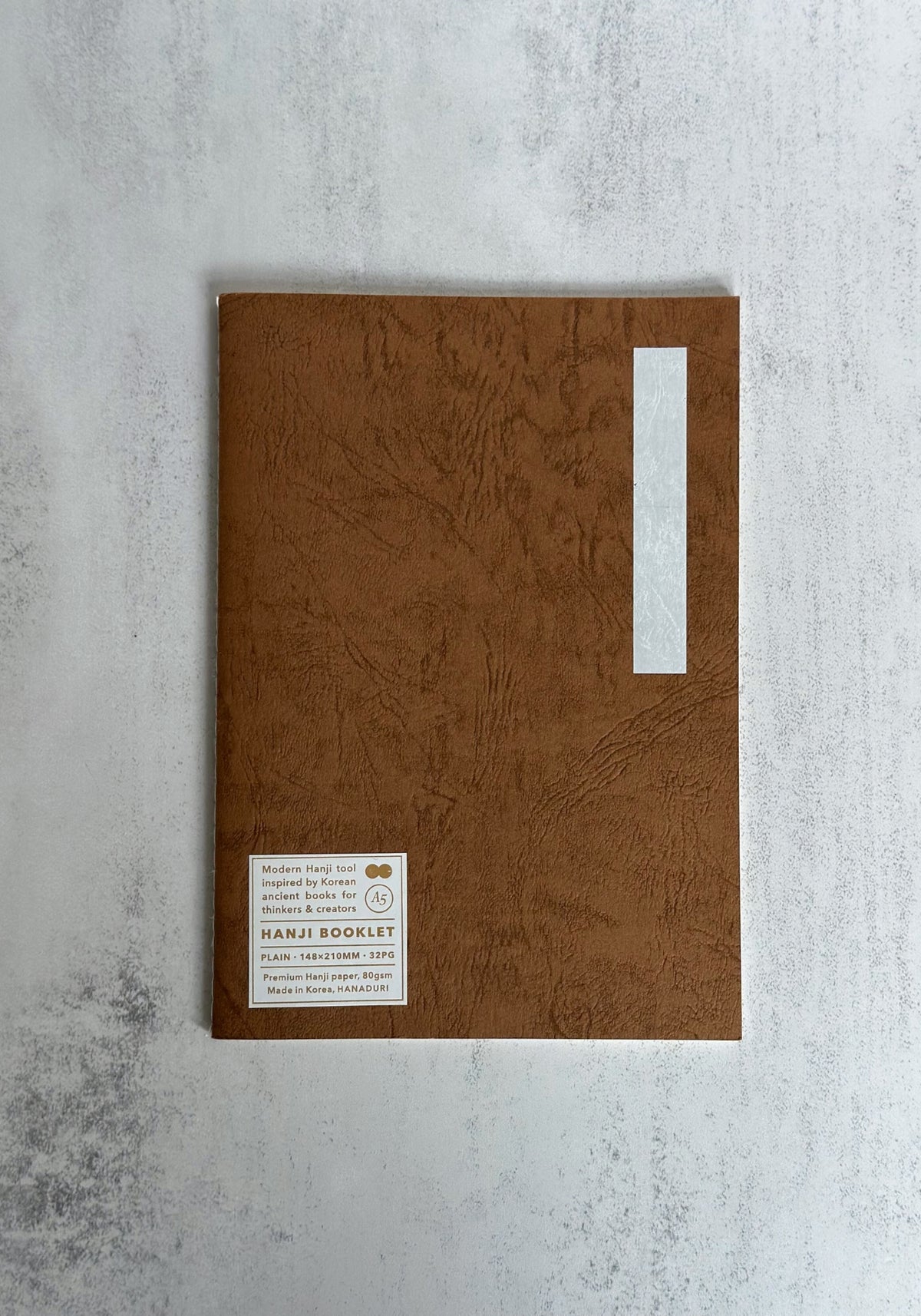 A collection of colourful A5 Hanji notebooks with textured covers fanned out on a grey surface.