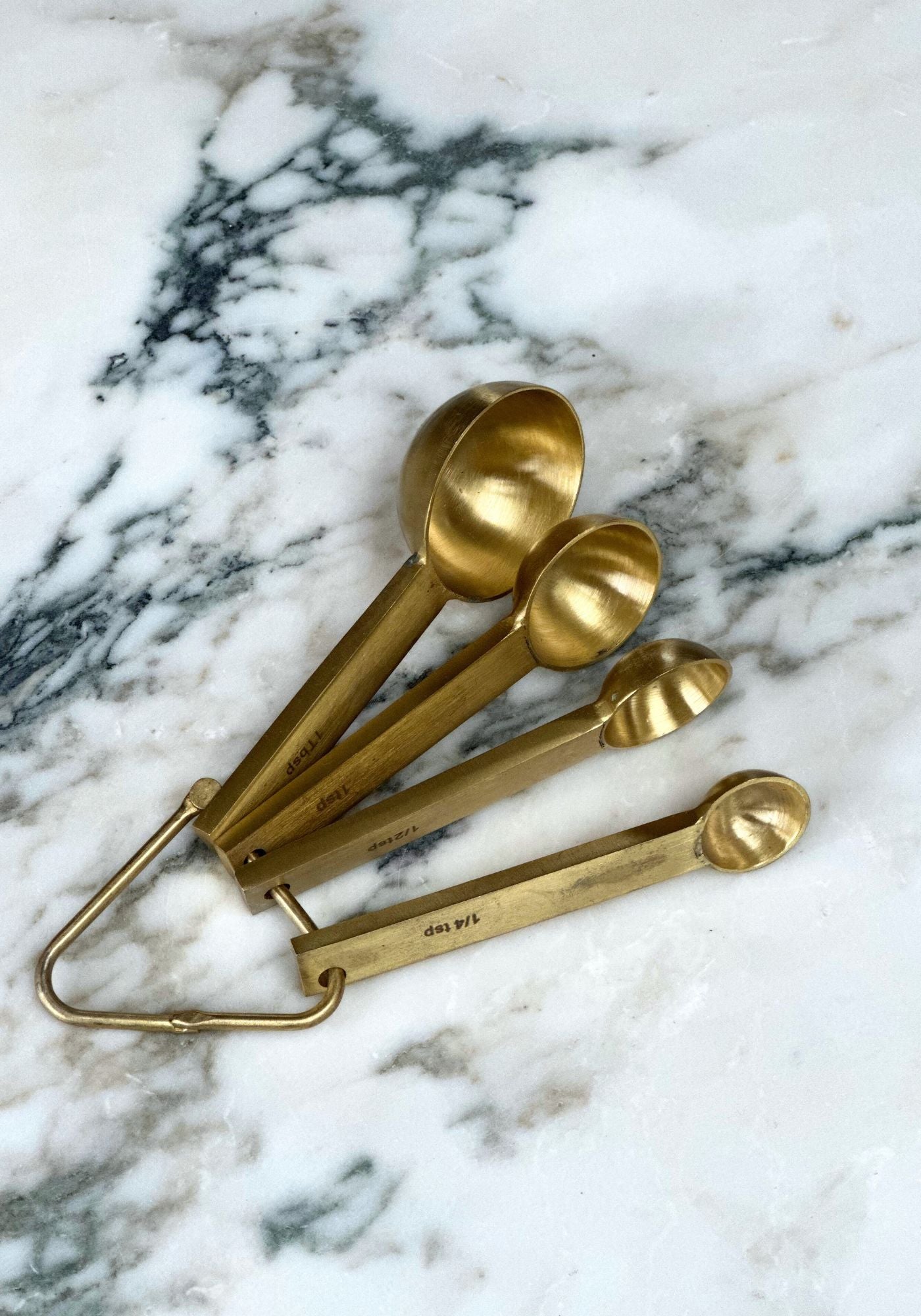 Set of gold measuring spoons on a marble surface