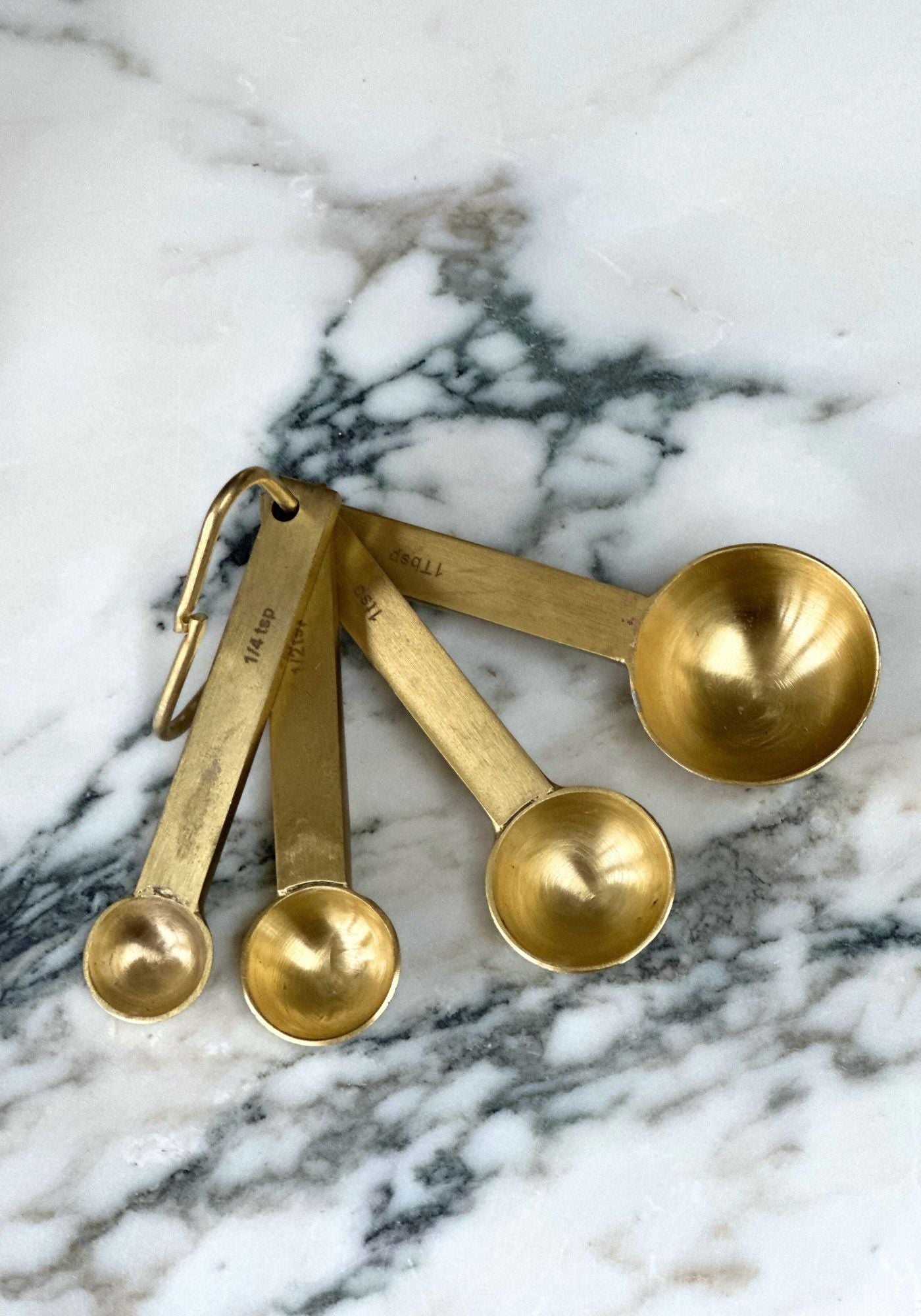 Set of brass measuring spoons on a marble surface