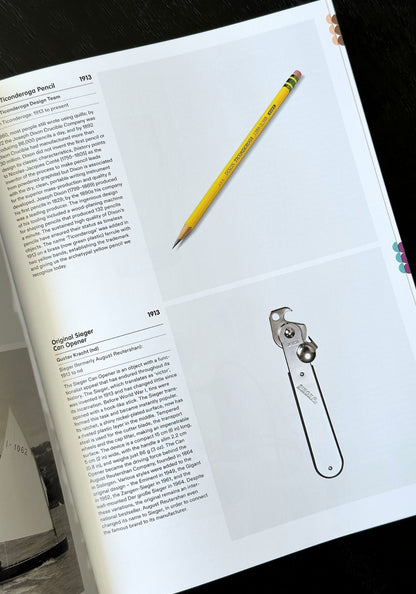 Open book with a pencil and metal tool on a white surface