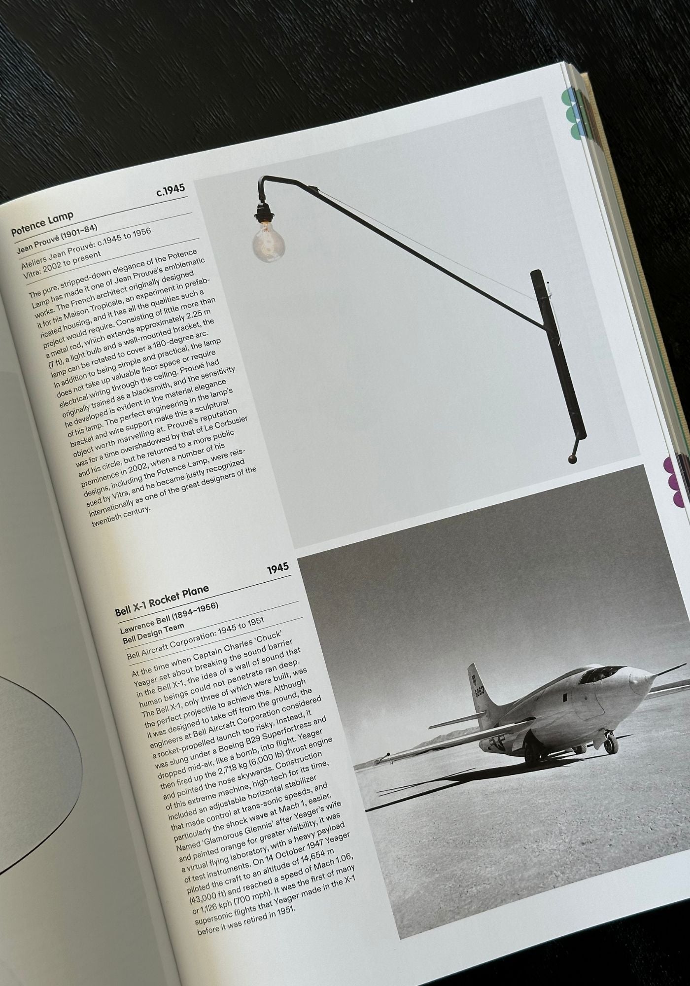 Open book with text and images of a plane and lamp on a dark surface