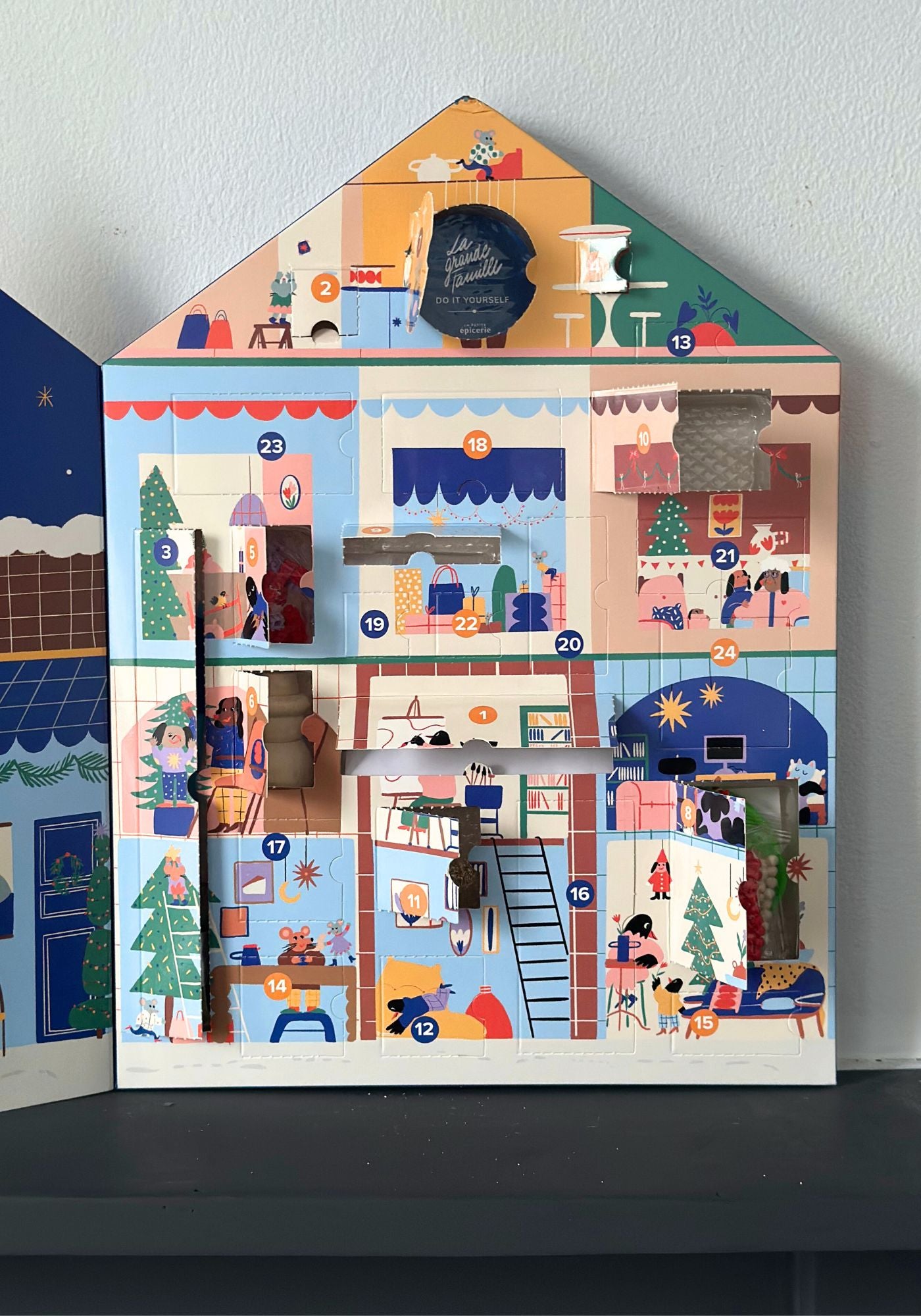 Advent calendar shaped like a house with colorful scenes on each door
