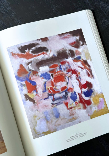 Open book with a colorful abstract painting on a dark surface