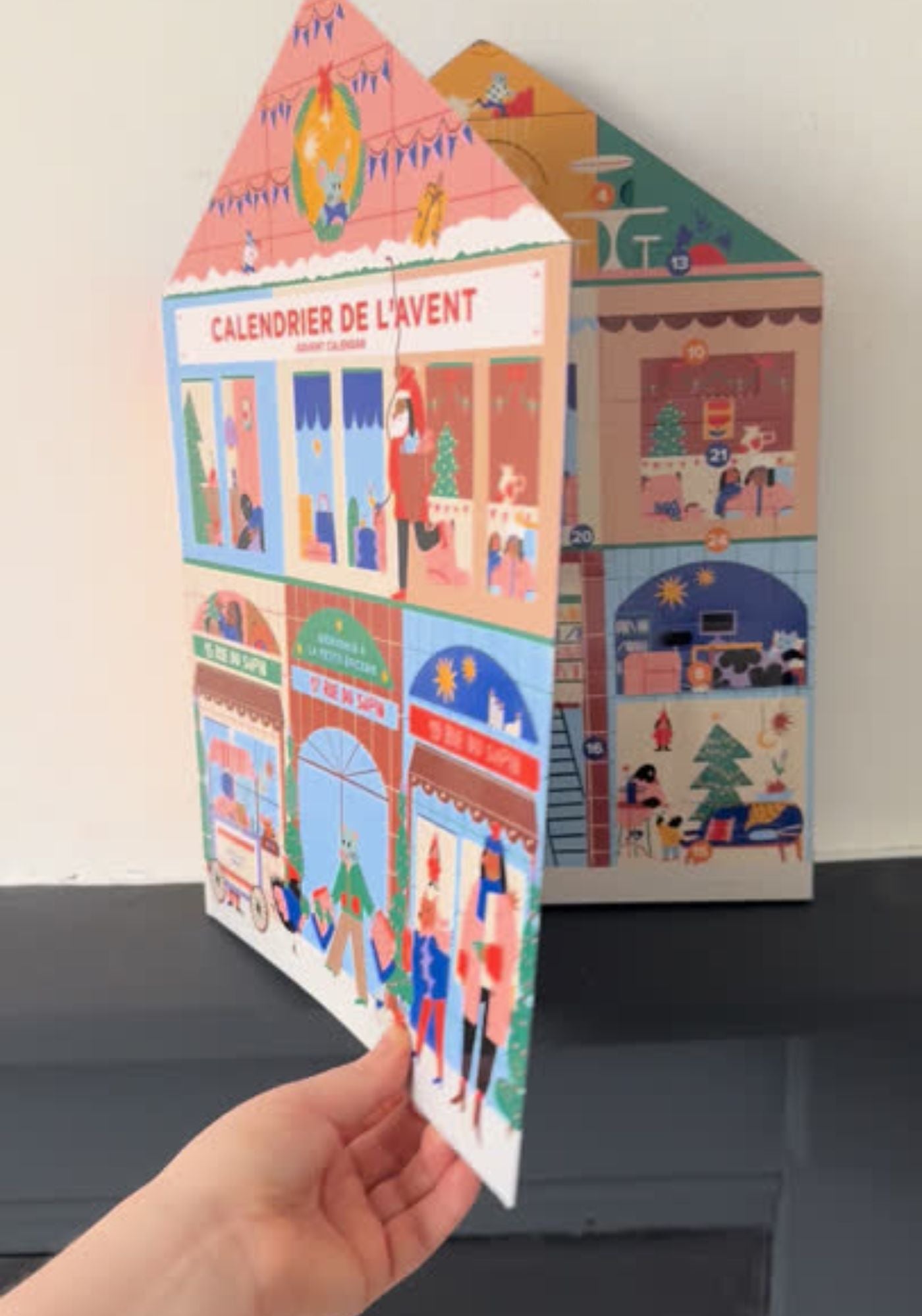 House-shaped Advent calendar with colorful illustrations on a neutral background