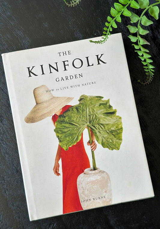 Book titled 'The Kinfolk Garden' on a dark surface with greenery.