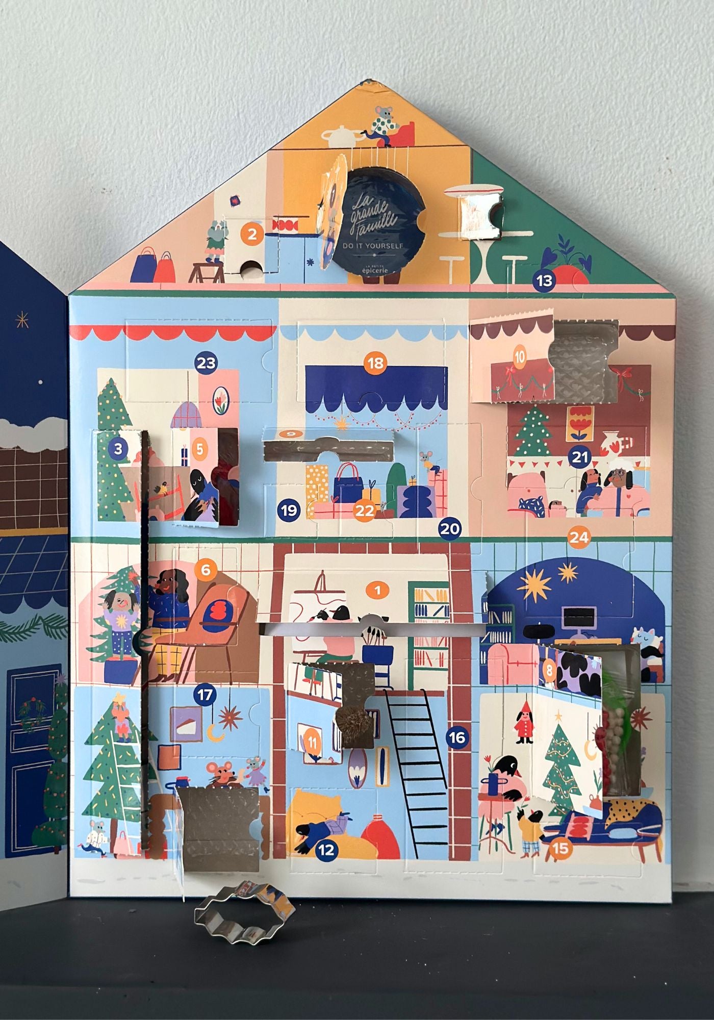 Decorative advent calendar shaped like a house with colorful scenes on each door