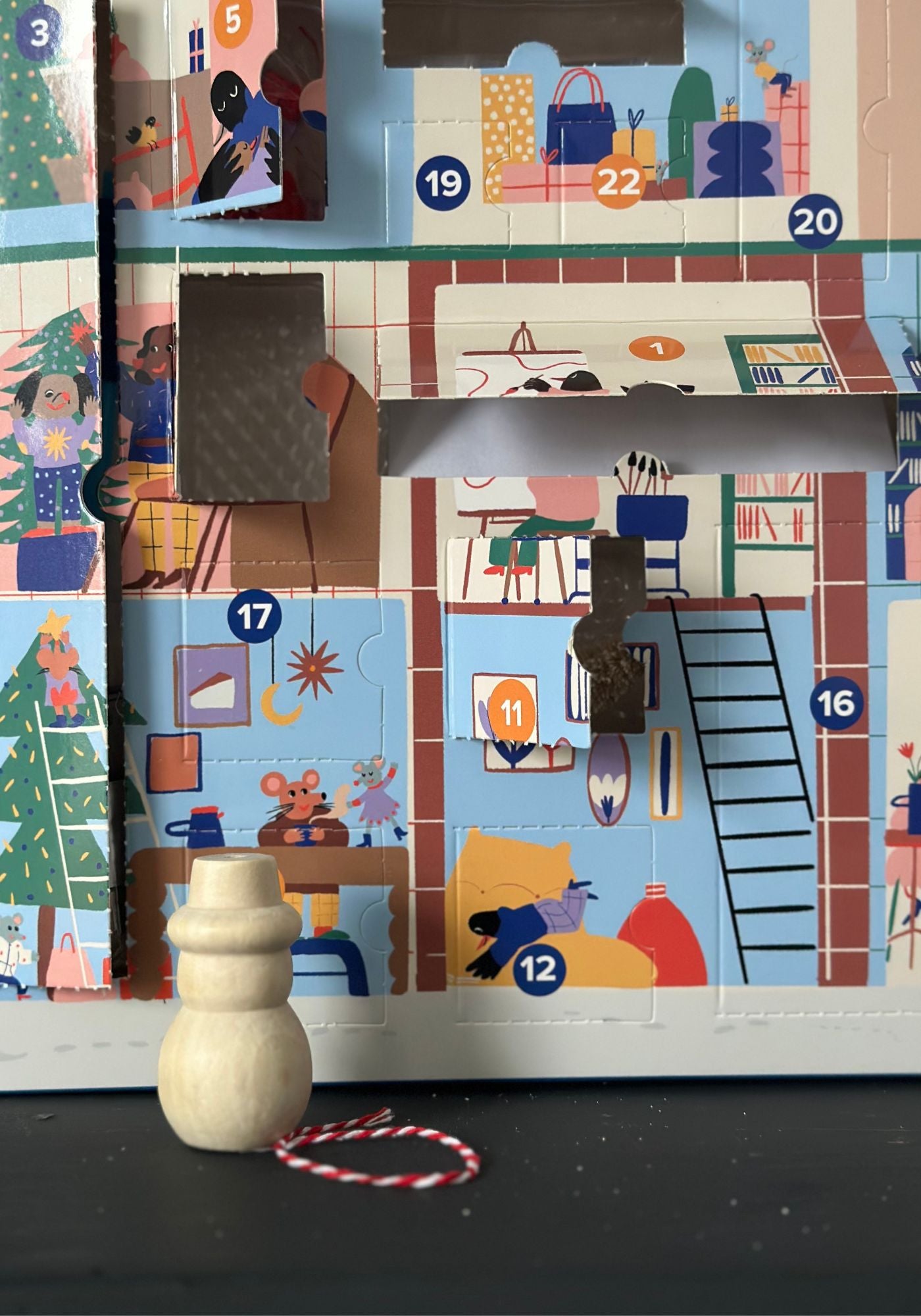 Children's advent calendar with wooden toy and string on a dark surface