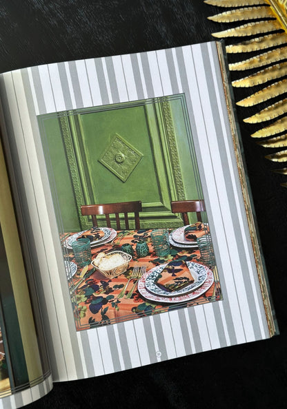 Dining room scene with a table set for a meal, framed by a book with striped pages.
