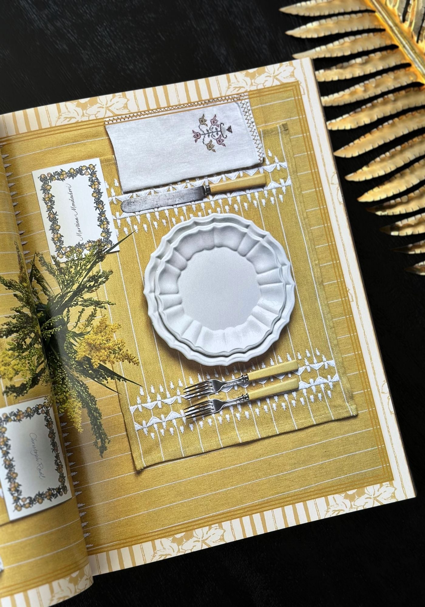 Table setting with white plate, silverware, and napkin on a yellow patterned placemat.