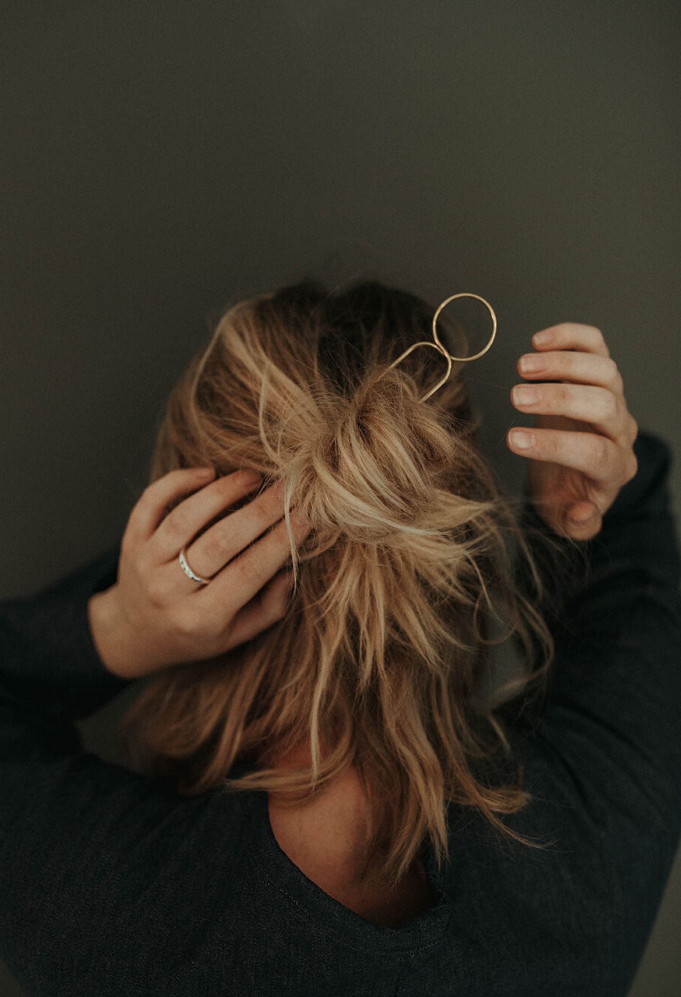 Minimalist gold-toned U-shaped hair pin securing a braided bun in dark hair.