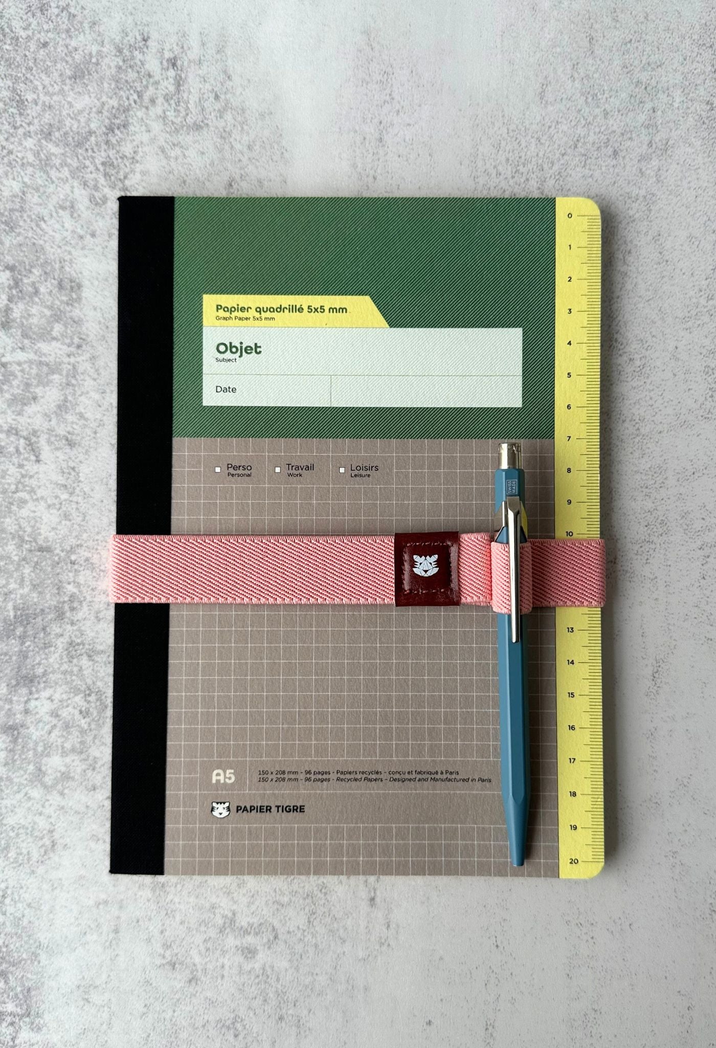 Colourful ribbed elastic notebook straps with pen loops and faux-leather patches on a notebook.