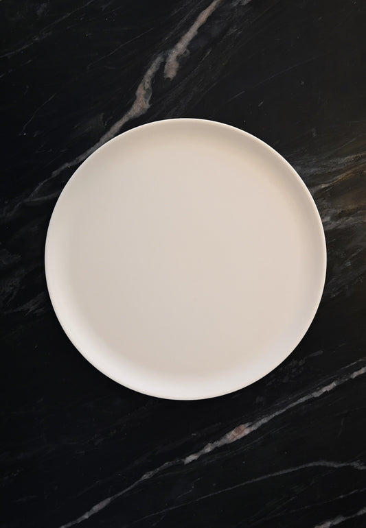Minimalist cream melamine plate and bowl set on a textured linen tablecloth.